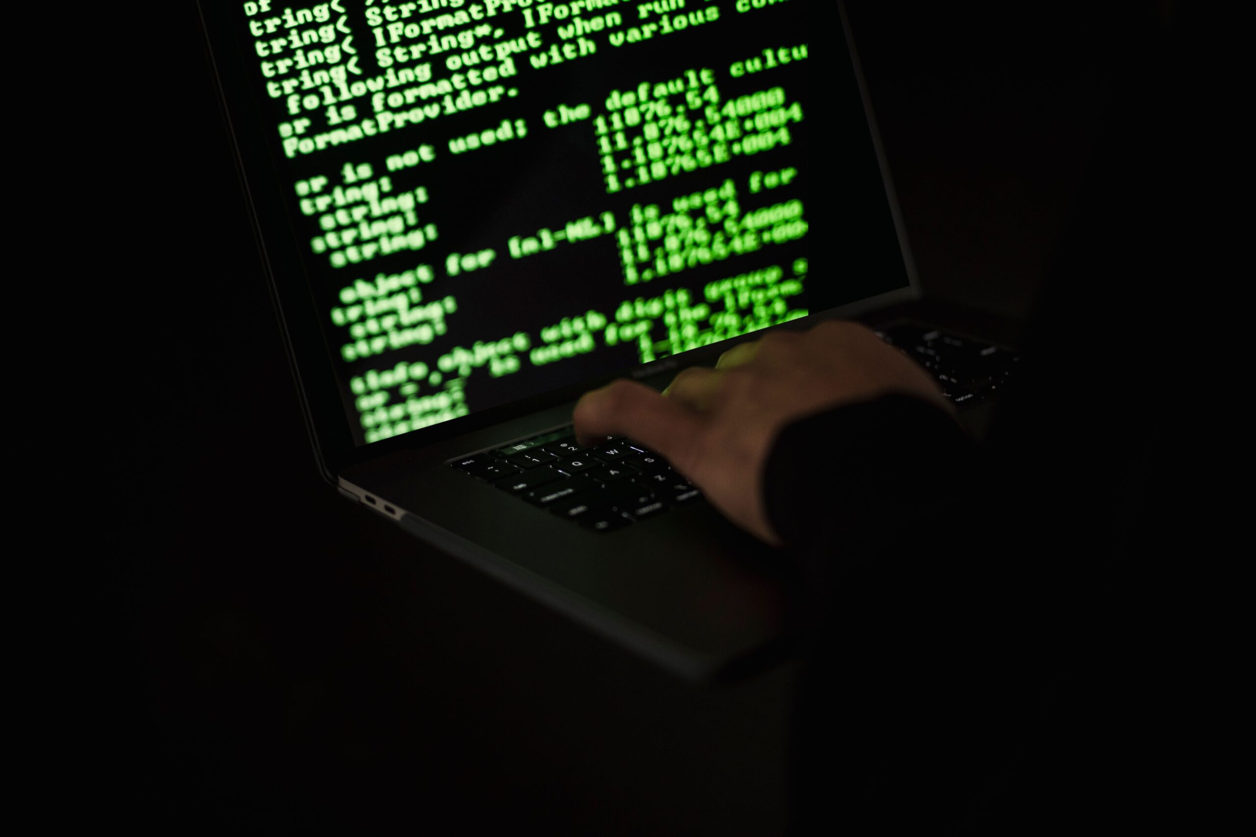 Vista de código de programación en una laptop con estética de hacker, representando la diferencia entre los mitos y la realidad de la ciberseguridad.
