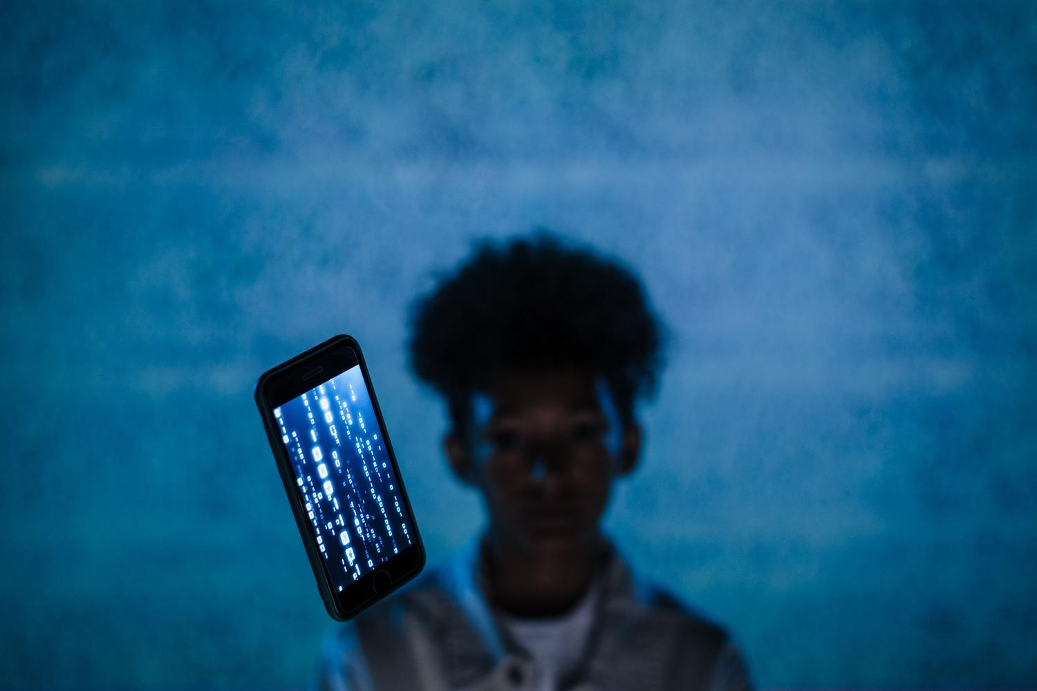 Primer plano de un iPhone con código binario digital en la pantalla, simbolizando el cifrado de datos y la seguridad avanzada de iCloud.