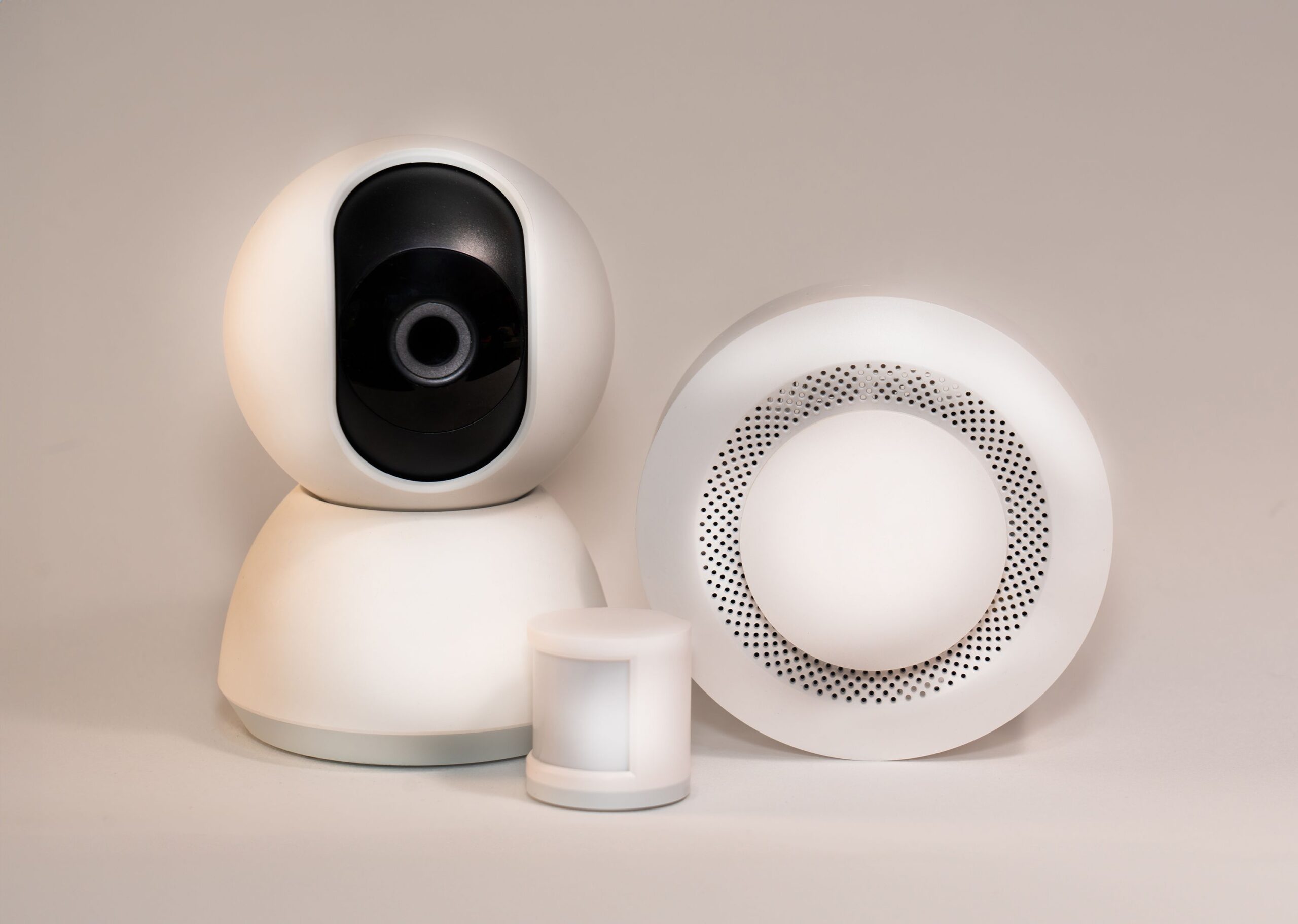 Kit de seguridad inteligente con cámara domo, sensor de movimiento y detector de humo sobre fondo neutro