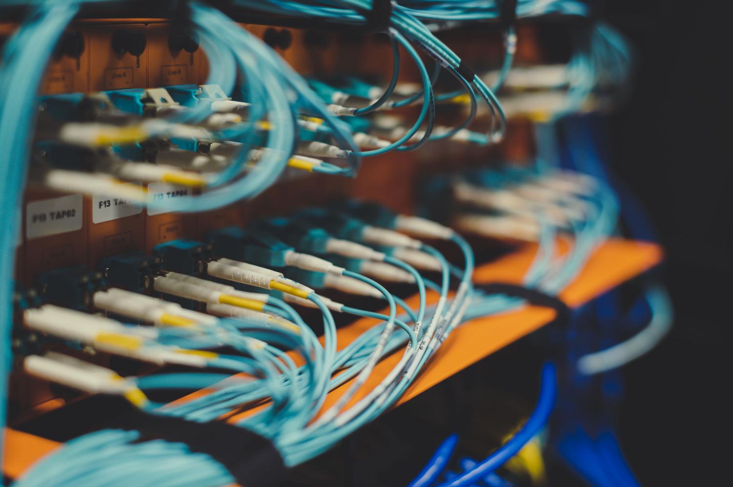 Primer plano de cables de fibra óptica conectados a un switch, ilustrando la segmentación física de una red.