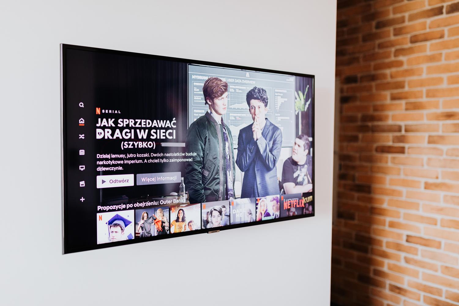 Smart TV minimalista instalada en una pared blanca, mostrando la interfaz de una plataforma de streaming.