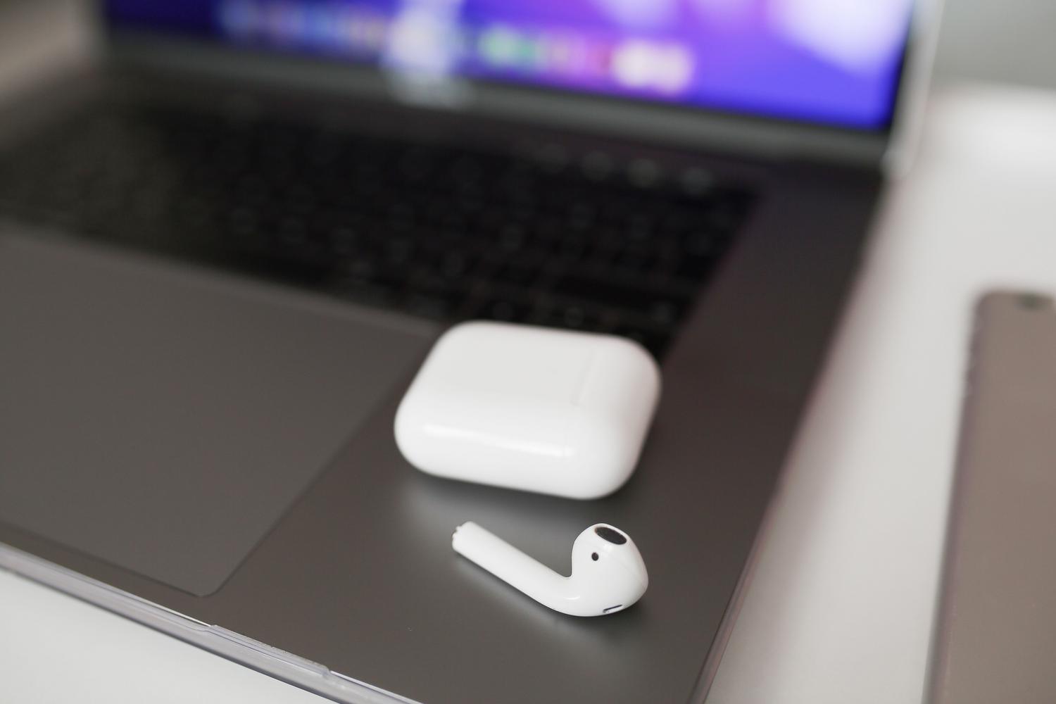 Primer plano de auriculares inalámbricos y su estuche sobre un ordenador portátil