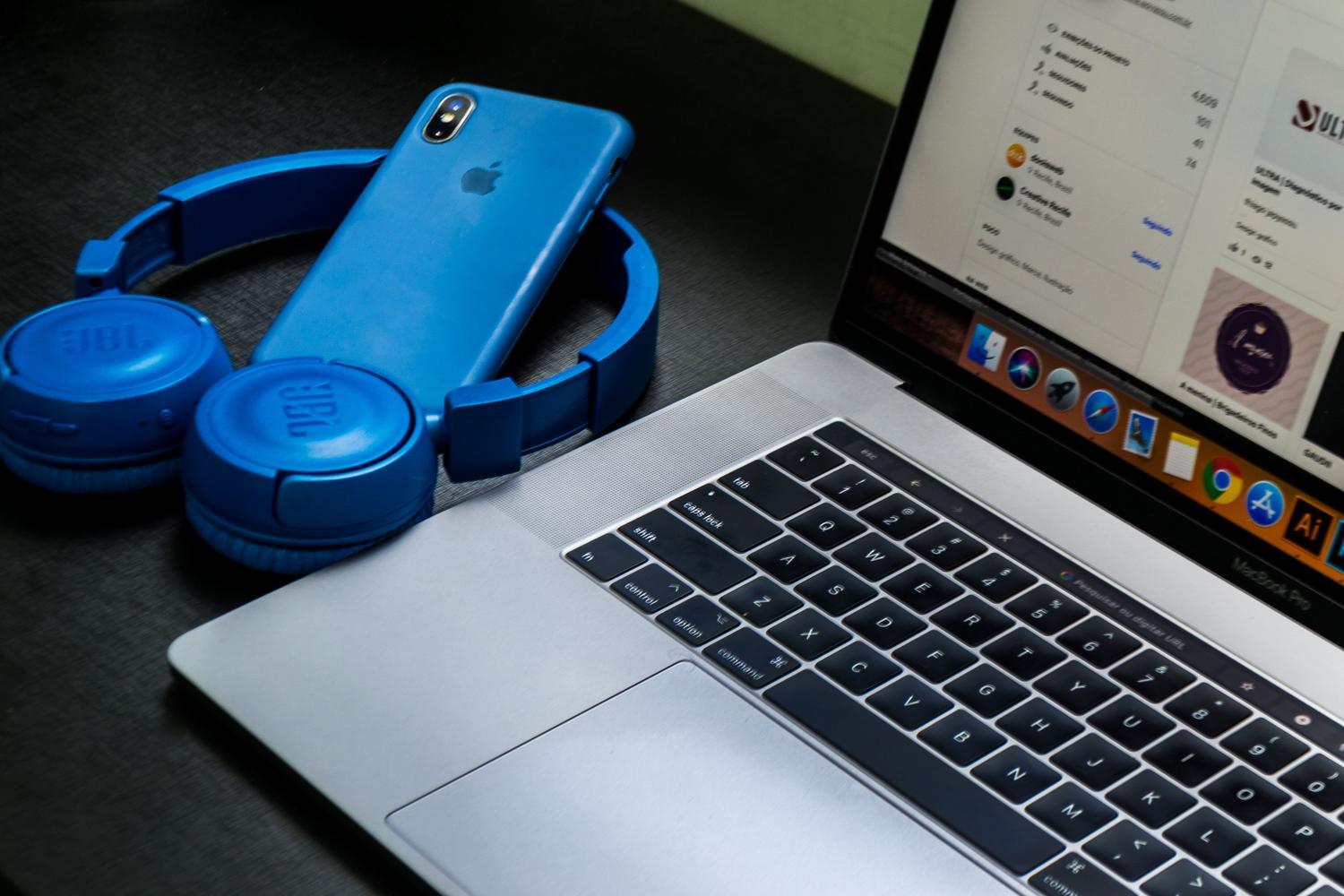 Configuración de oficina con MacBook Pro y auriculares inalámbricos azules