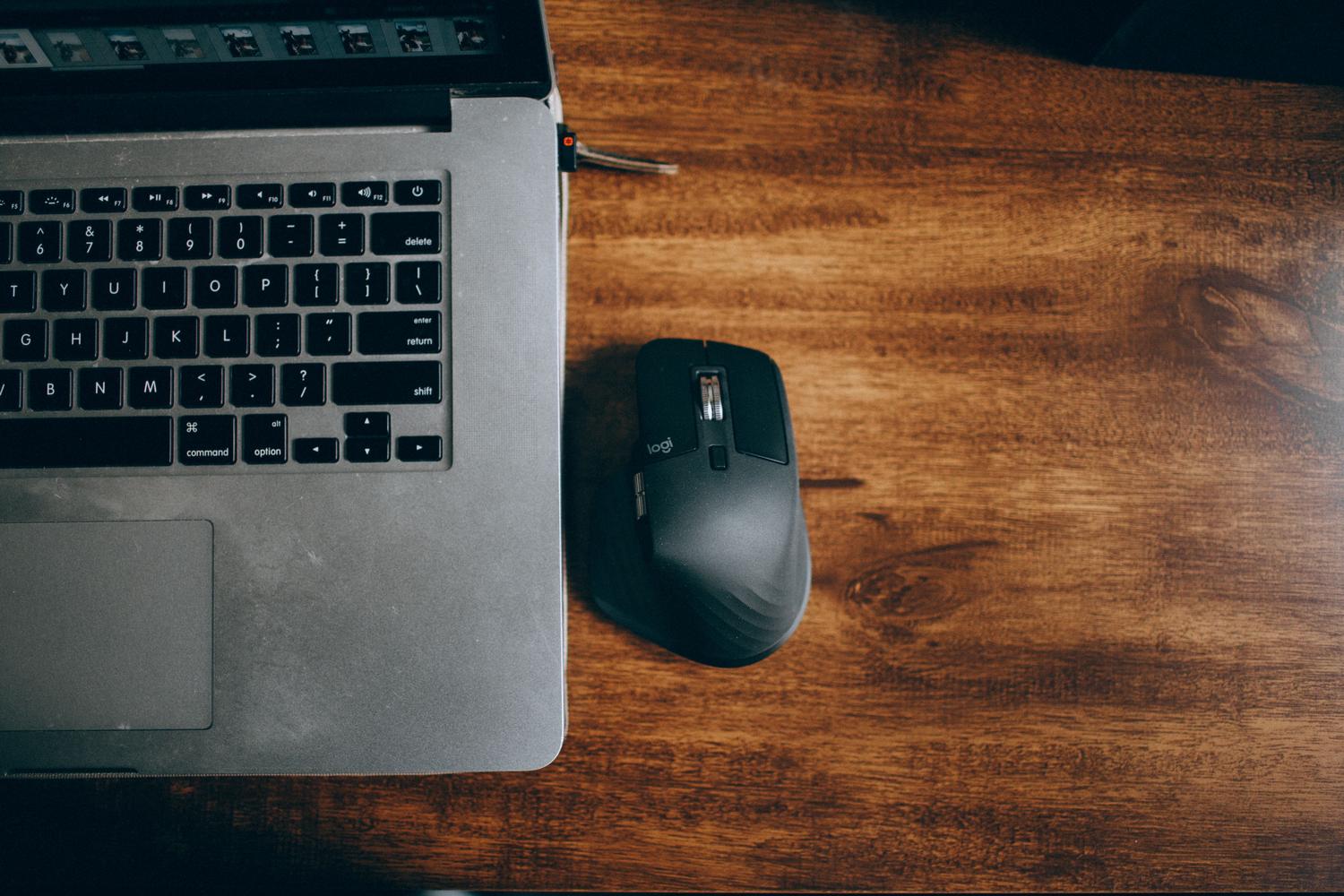 Vista superior de un escritorio con MacBook y un ratón inalámbrico negro