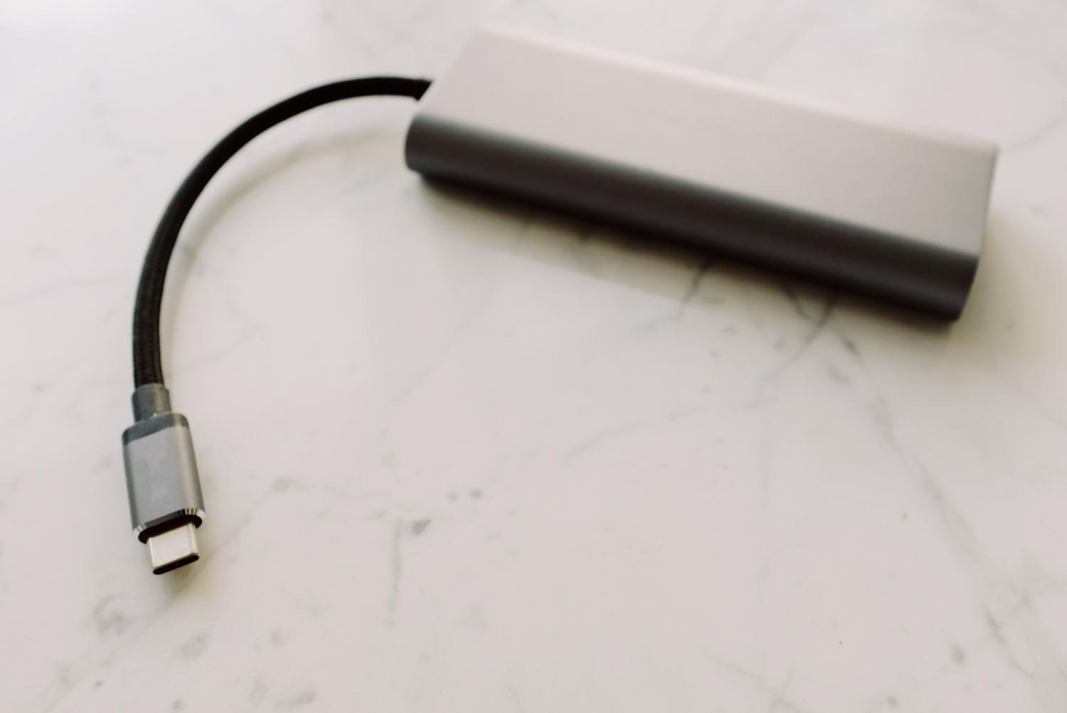 Detalle de un adaptador USB-C sobre una superficie de mármol, representando los accesorios necesarios para conectar periféricos en Mac modernos.