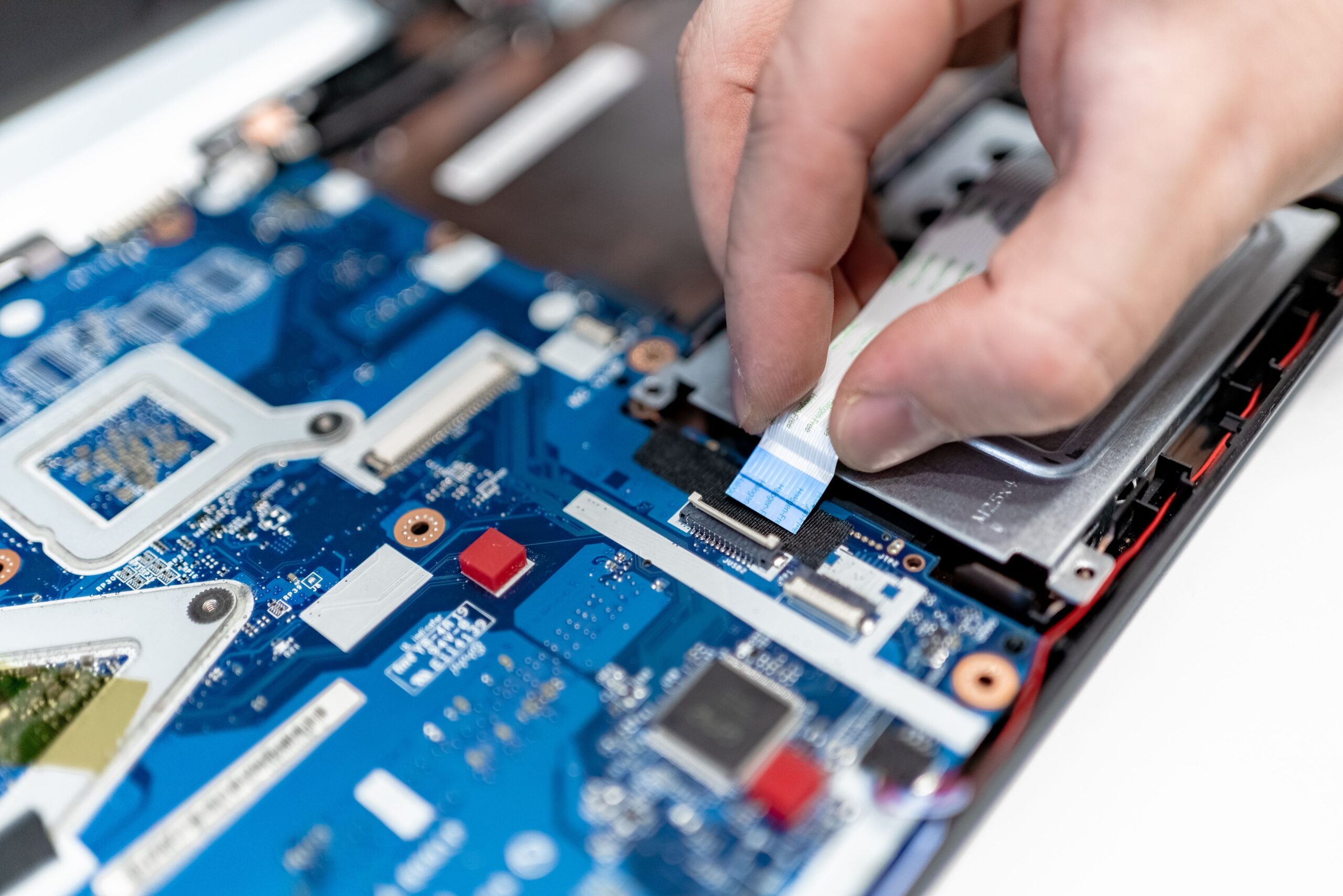 Técnico reparando la placa de circuito de un ordenador portátil, ilustrando el proceso de diagnóstico y reparación de hardware.