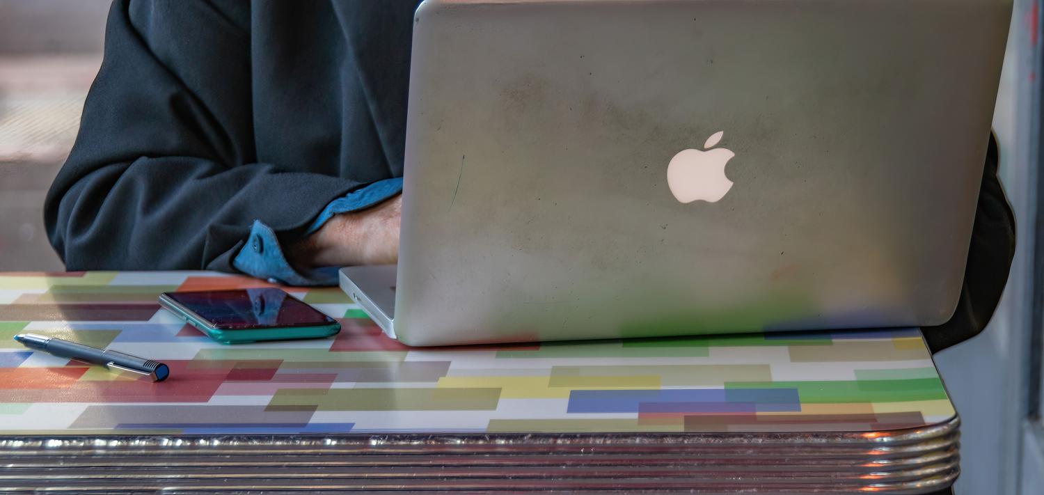 Persona utilizando un MacBook en un entorno de trabajo moderno, representando la experiencia del usuario al buscar archivos. Persona utilizando un MacBook en un entorno de trabajo moderno, representando la experiencia del usuario al buscar archivos.
