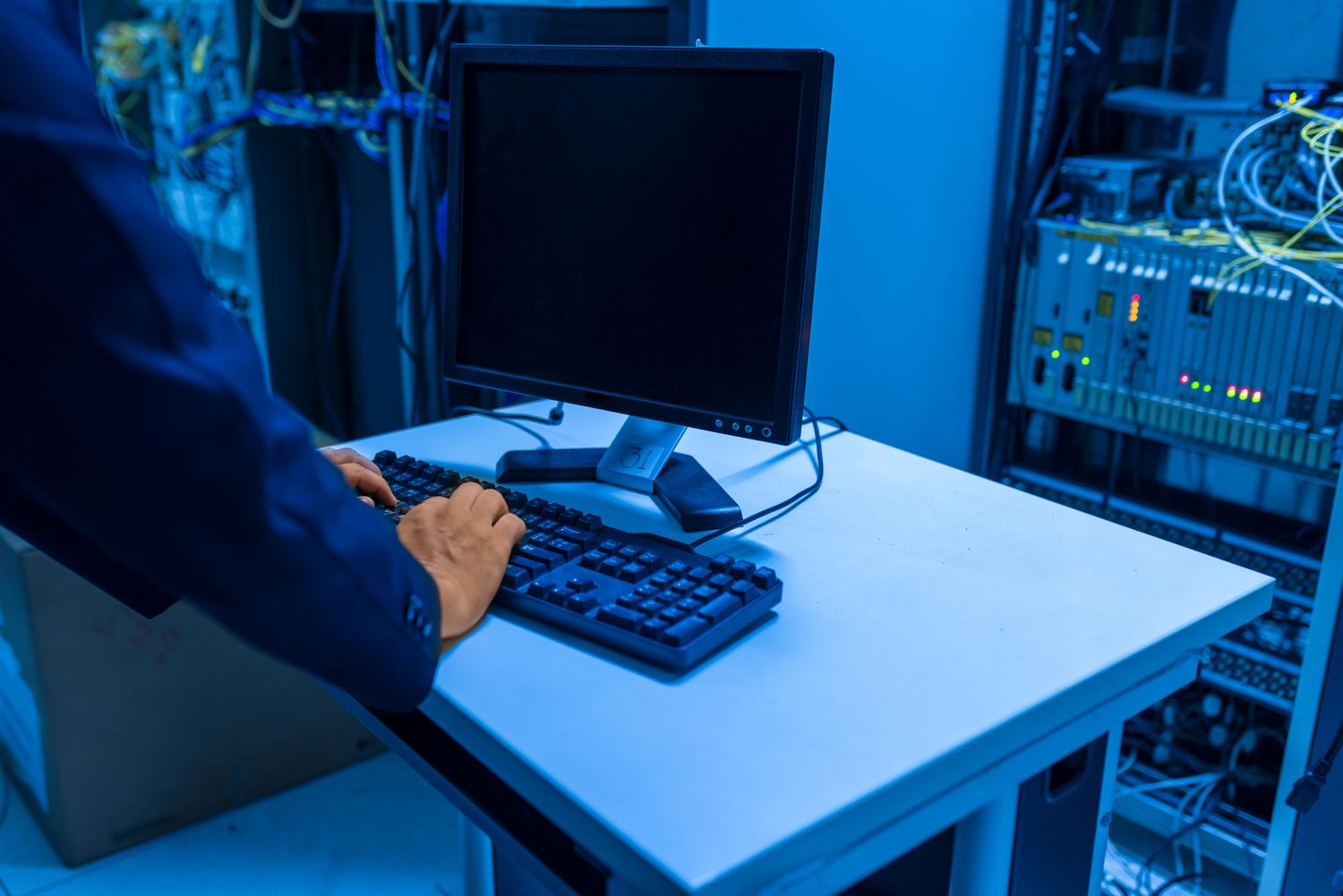 Técnico de IT gestionando sistemas en una sala de servidores, representando la gestión profesional de equipos.