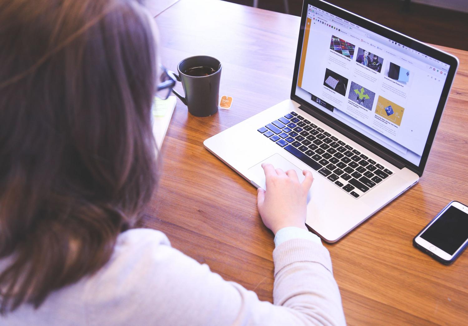 Persona utilizando un MacBook en un escritorio de madera para navegar por la web, representando la optimización de la navegación. Persona utilizando un MacBook en un escritorio de madera para navegar por la web, representando la optimización de la navegación.