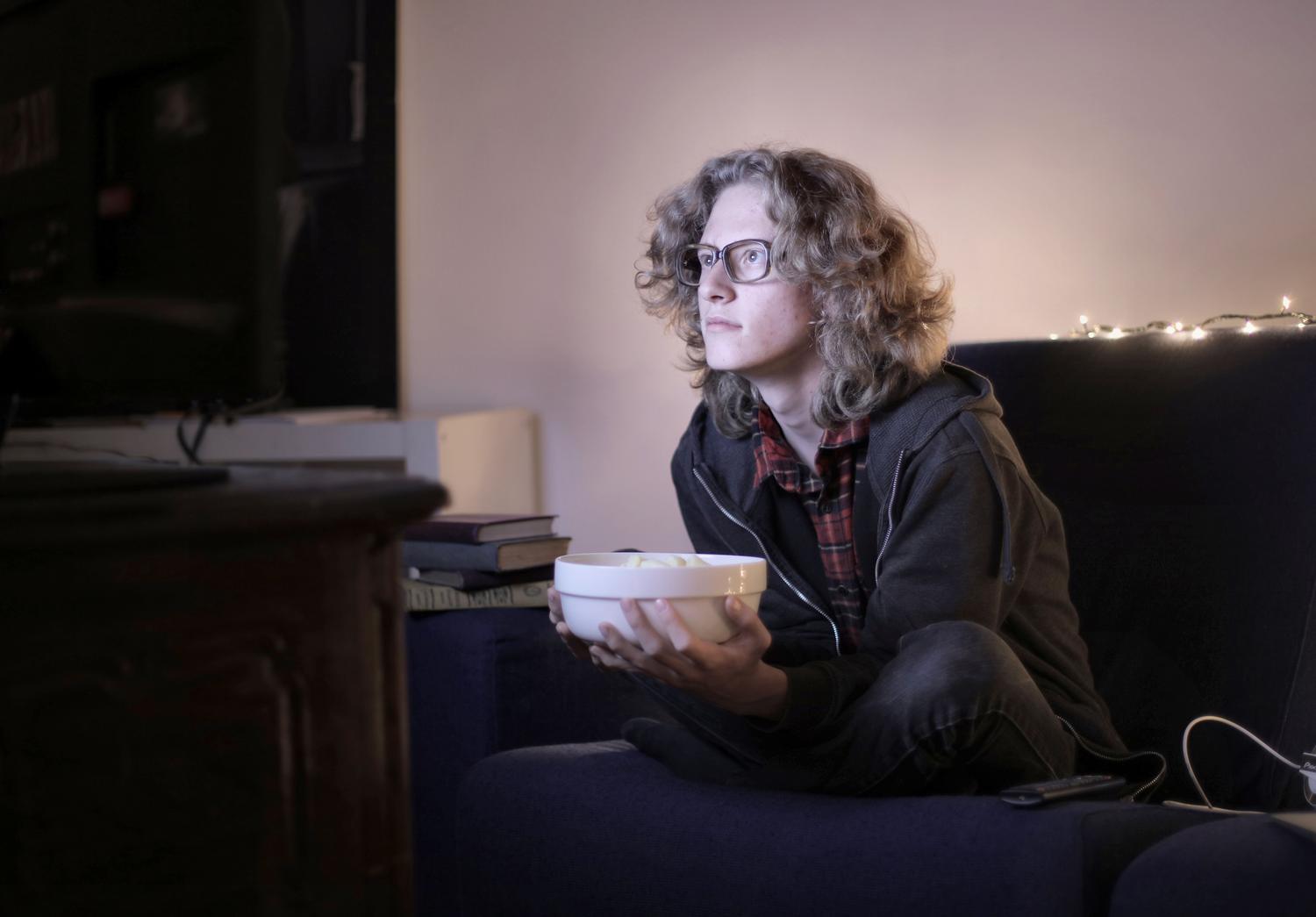 Persona concentrada viendo una película con palomitas, capturando la sensación inmersiva de una sala de cine doméstica.