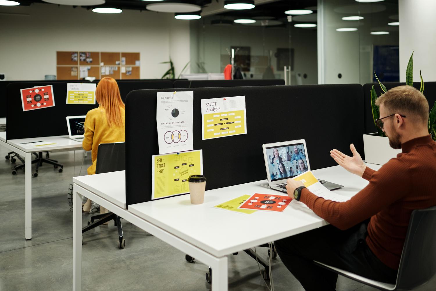 Profesional realizando una videollamada de trabajo en un entorno de oficina moderno, representando la colaboración virtual y el trabajo híbrido.