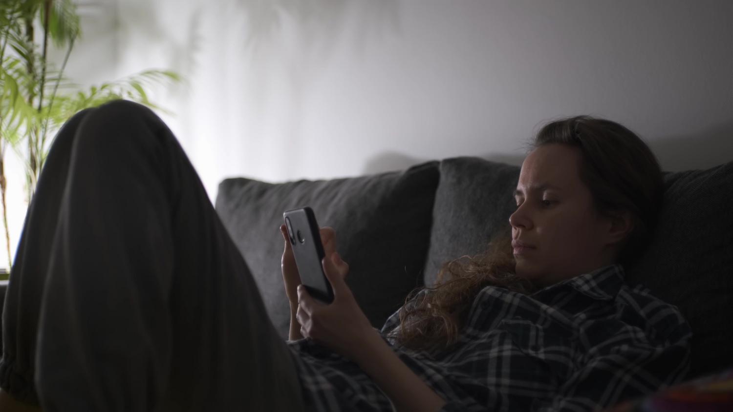 Persona utilizando un smartphone en un salón con iluminación tenue, creando un ambiente relajado