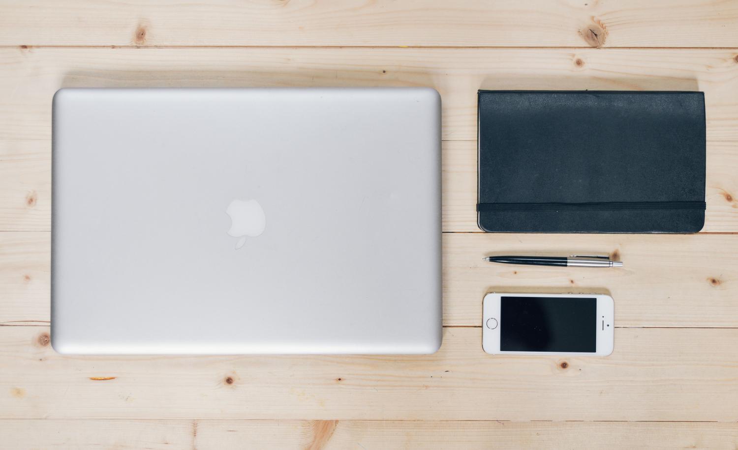 Espacio de trabajo minimalista y organizado con un portátil cerrado, una libreta y un smartphone, representando un flujo de trabajo híbrido y productivo. Espacio de trabajo minimalista y organizado con un portátil cerrado, una libreta y un smartphone, representando un flujo de trabajo híbrido y productivo.
