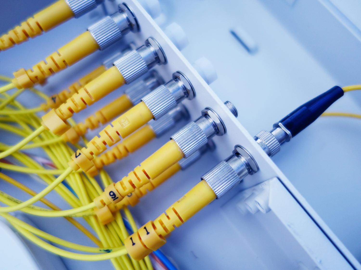 Primer plano de cables de fibra óptica amarillos en un servidor, representando la infraestructura de alta velocidad.