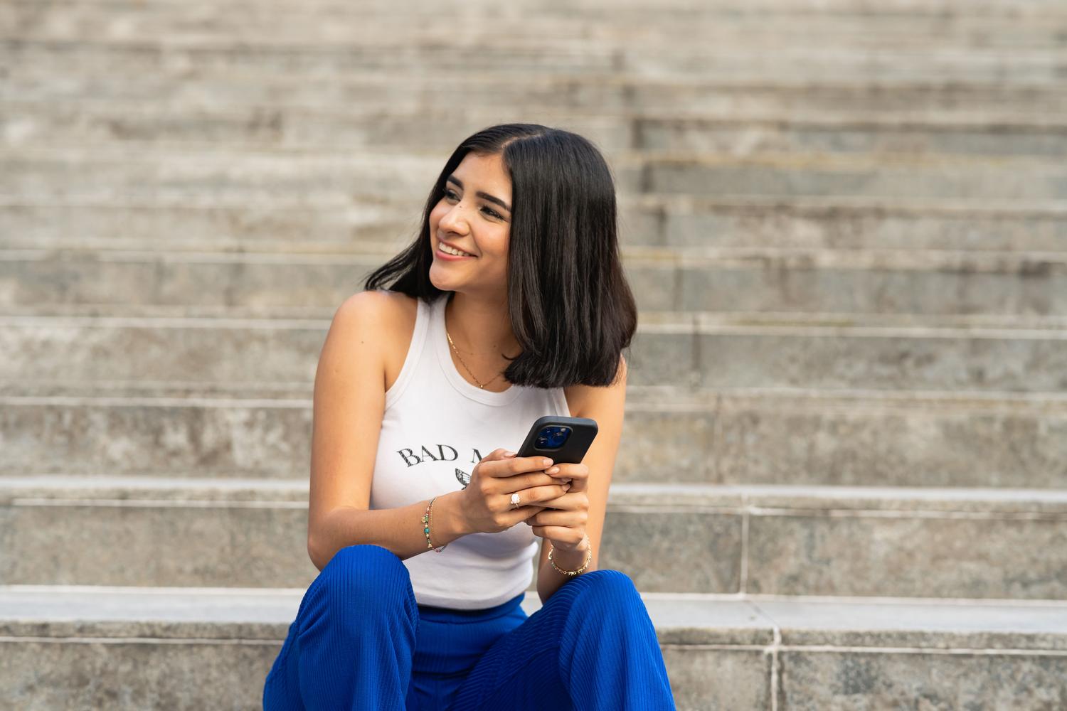 Mujer joven sonriente utilizando su teléfono móvil tras solucionar los errores de la Google Play Store