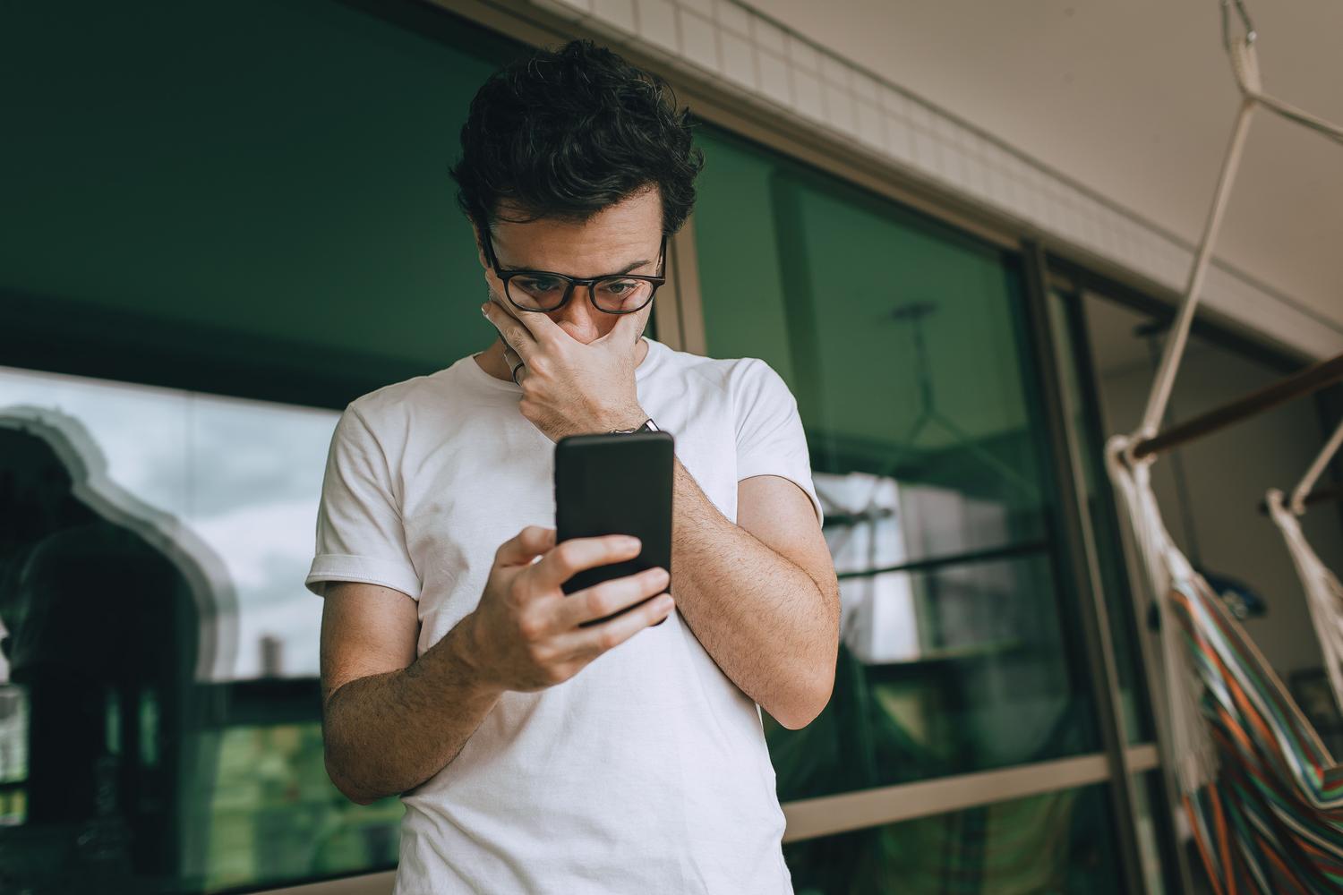 Hombre sorprendido y preocupado al ver un mensaje de error inesperado en su dispositivo Android