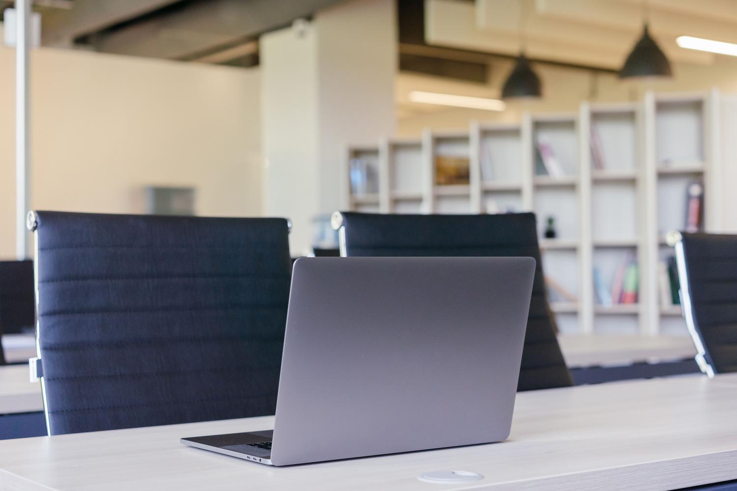 Interior de oficina contemporáneo con un portátil elegante sobre la mesa, reflejando la estética nativa de macOS.