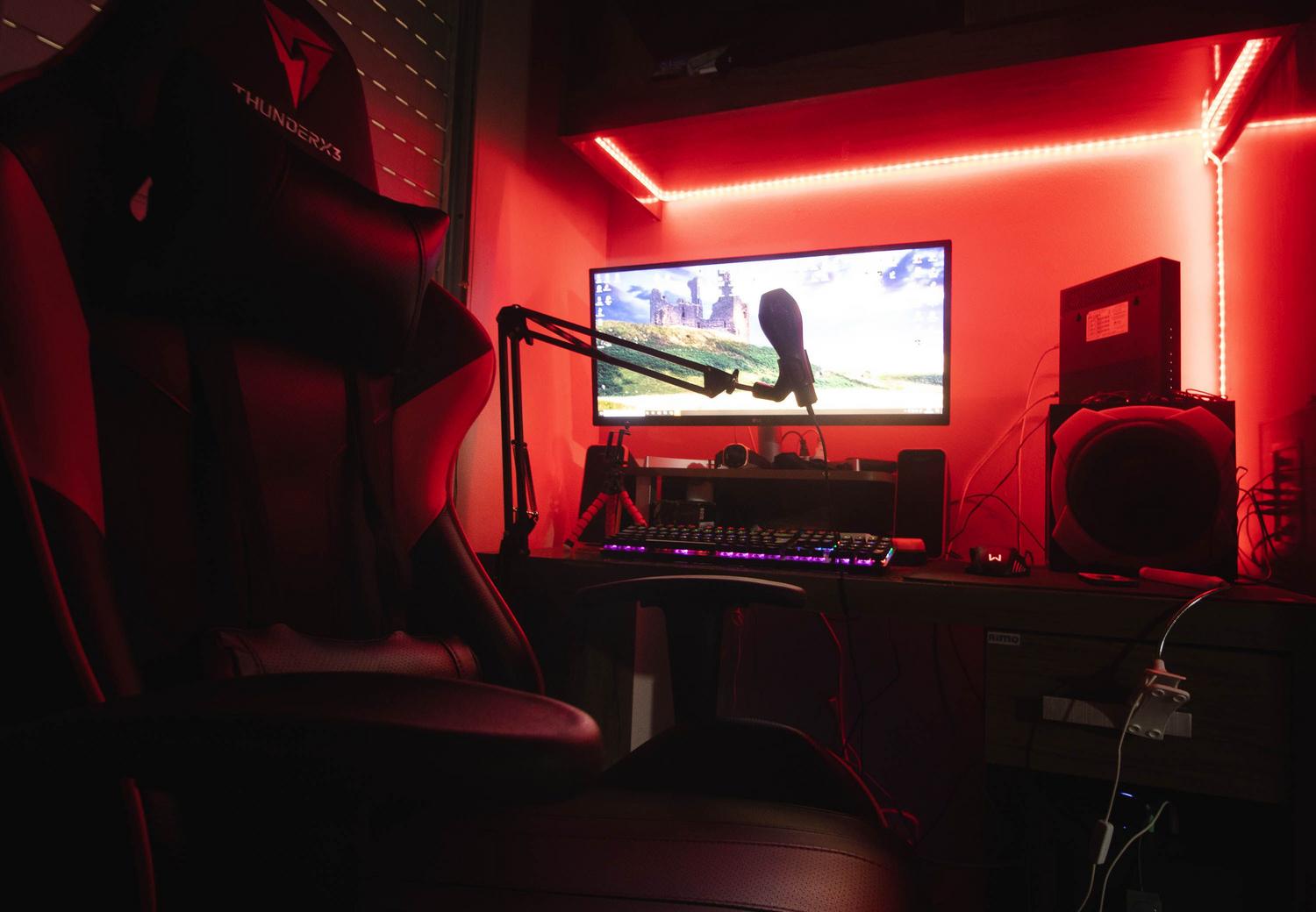 Setup gaming inmersivo con iluminación LED roja y periféricos profesionales para creadores de contenido.