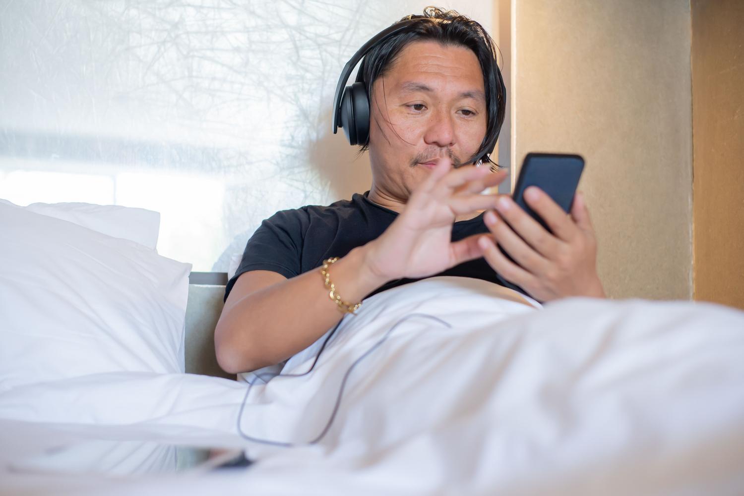Hombre joven utilizando auriculares y un smartphone en un entorno relajado, representando al público objetivo de la Generación Z y Millennials en Spotify.