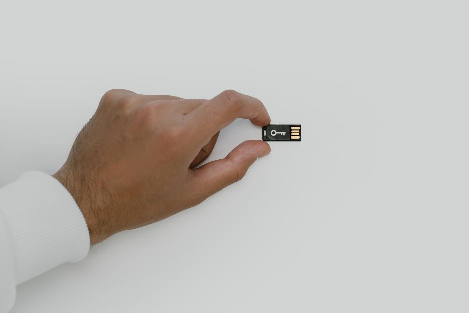 Primer plano de una mano sosteniendo una llave de seguridad USB, ilustrando la autenticación mediante llaves físicas para blindar la cuenta de Google.