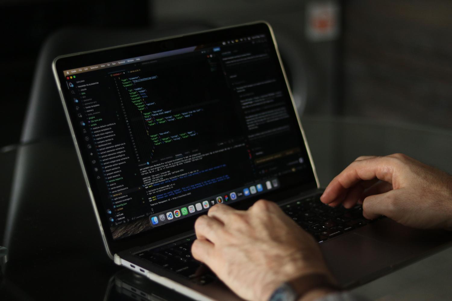 Detalle de las manos de un desarrollador escribiendo código de programación en un ordenador portátil