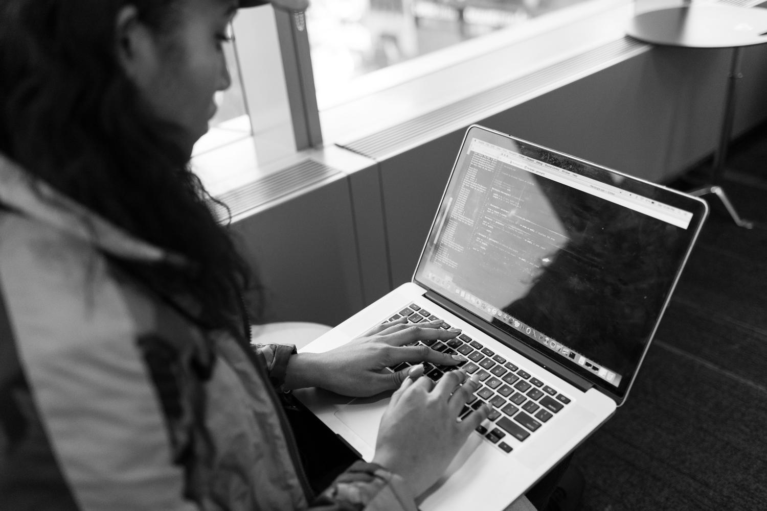 Una mujer programando en un portátil en una oficina moderna, aportando diversidad y un elemento humano al contenido técnico.