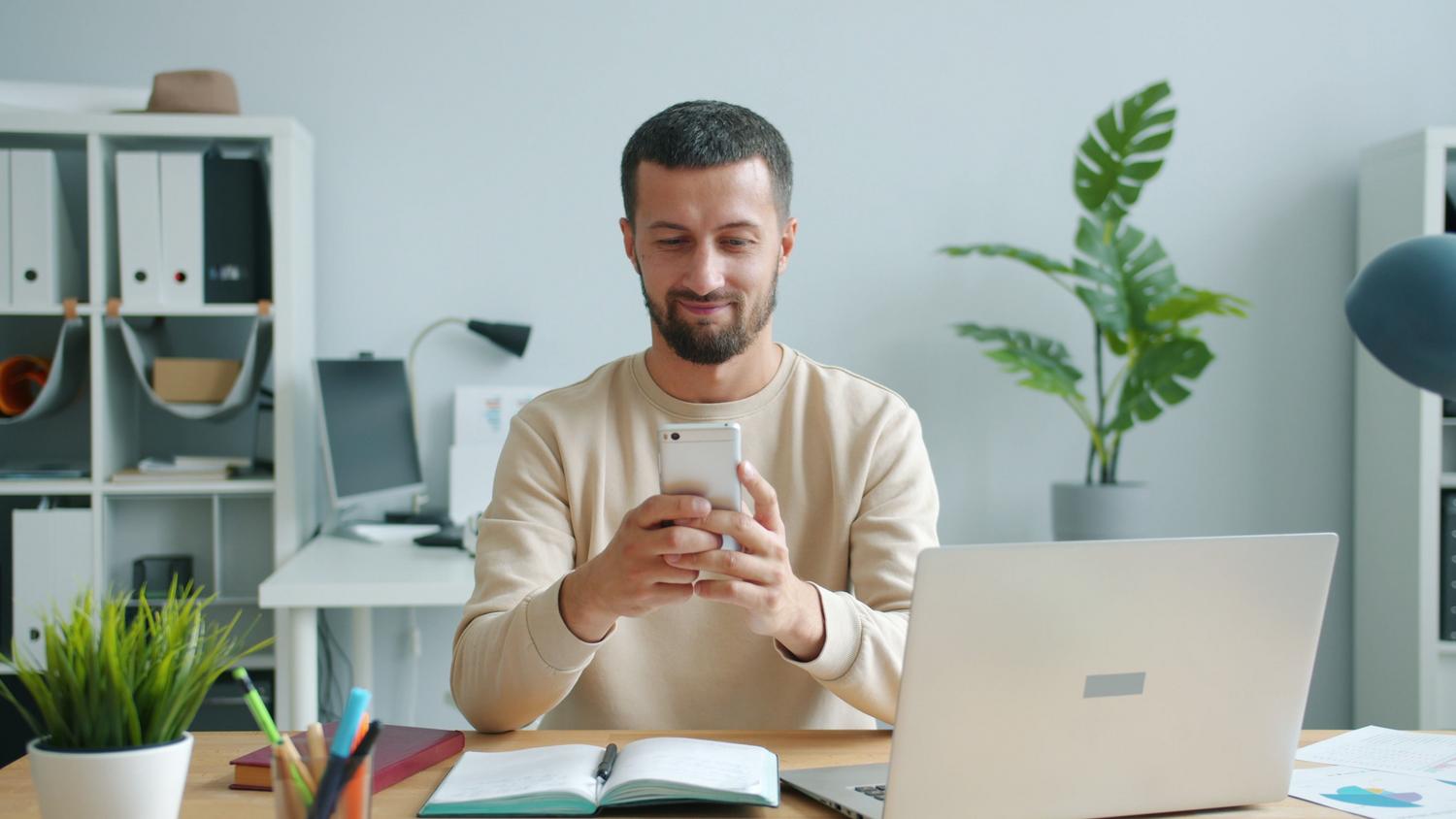 Persona concentrada revisando información en su teléfono móvil en una oficina moderna y luminosa. Persona concentrada revisando información en su teléfono móvil en una oficina moderna y luminosa.