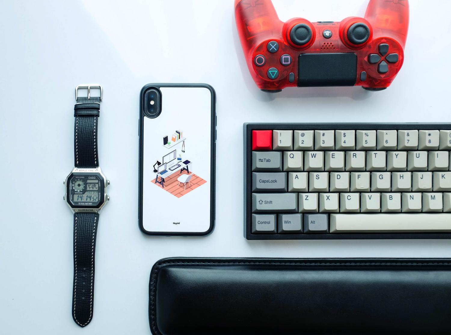Composición cenital de gadgets tecnológicos que incluye un smartphone, un mando de videojuegos rojo y un teclado mecánico.