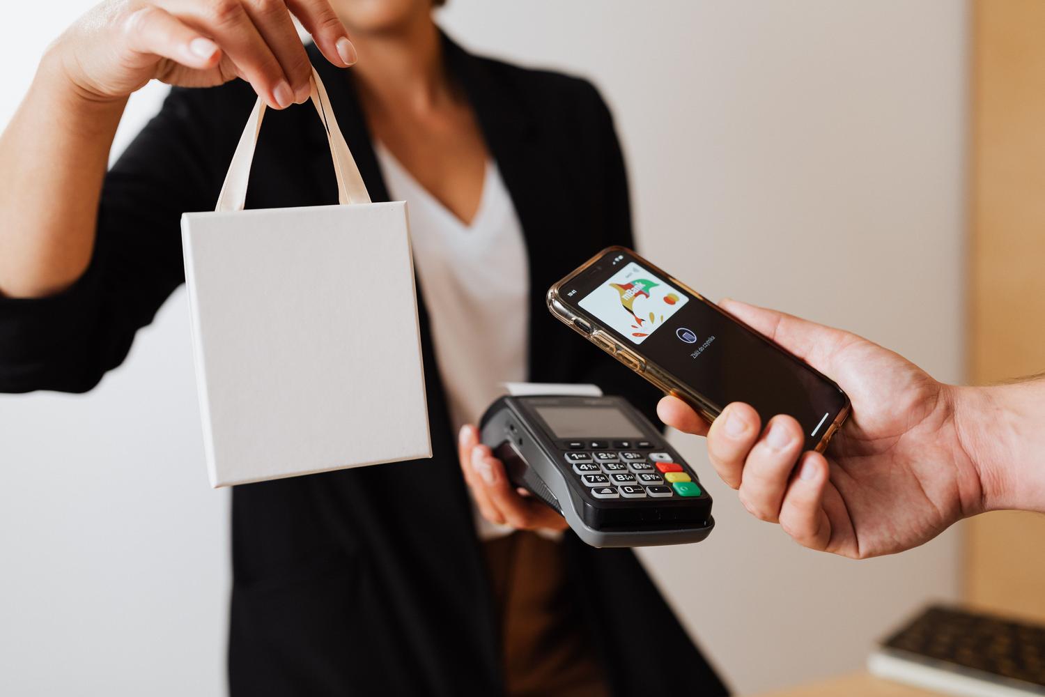 Cliente pagando con el móvil y recibiendo su compra en una tienda.