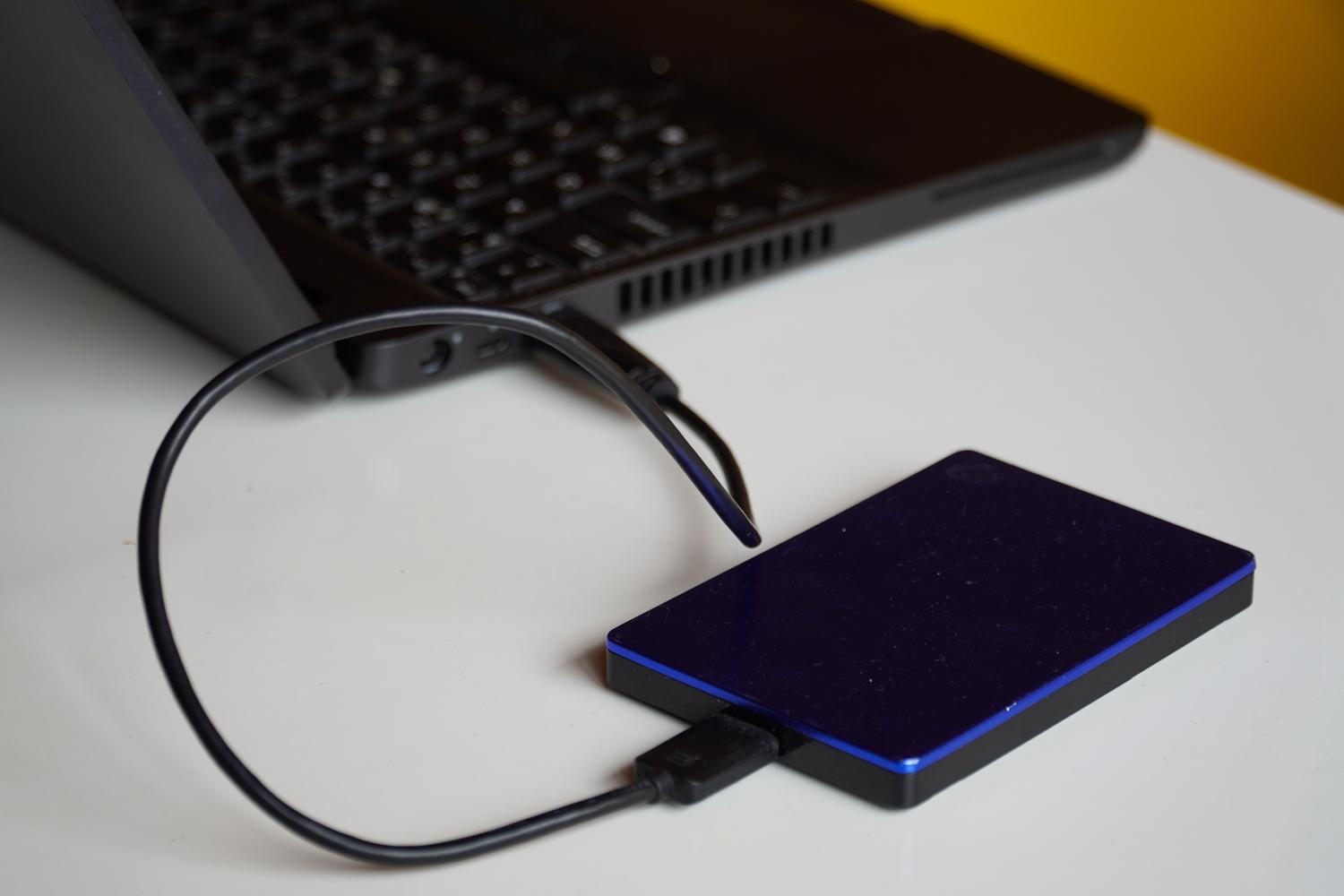 Disco duro externo conectado a un ordenador portátil, representando la realización de una copia de seguridad de datos.