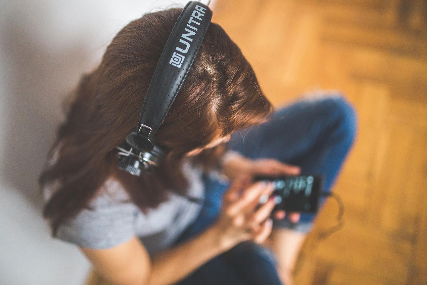 Vista cenital de una mujer utilizando su teléfono móvil y escuchando música con auriculares