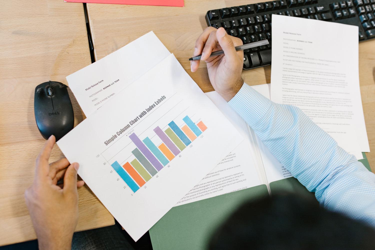Profesional revisando un informe con gráficos de barras y formularios de datos en un entorno de oficina.