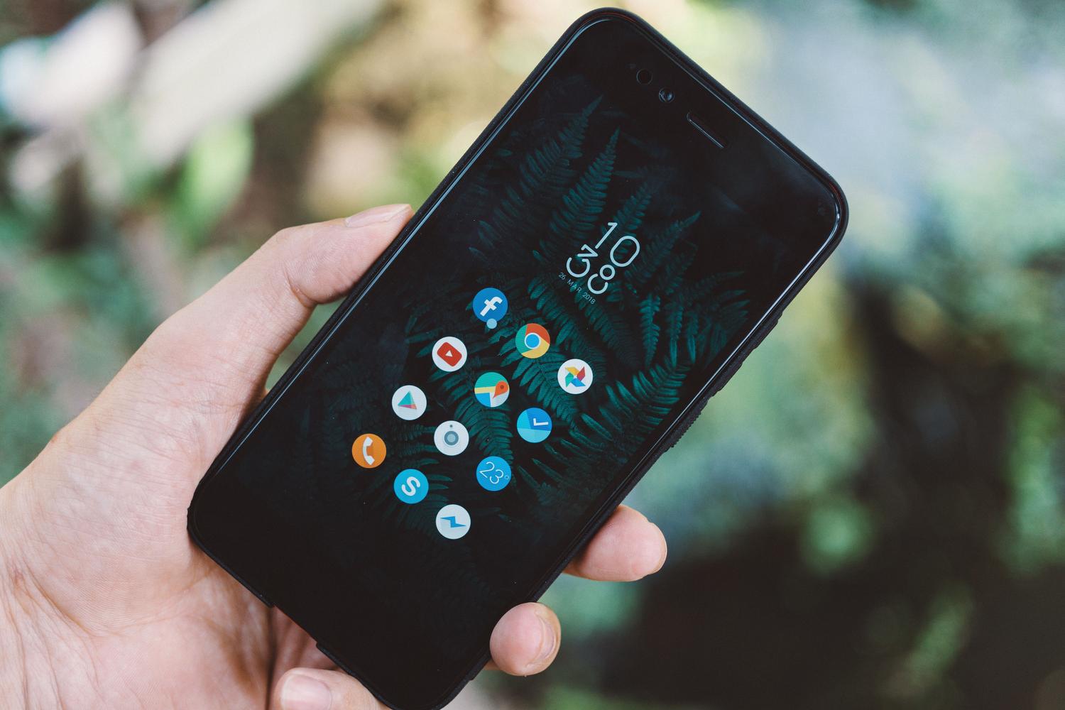 Primer plano de una mano sosteniendo un teléfono móvil con diversos iconos de aplicaciones en pantalla, ideal para ilustrar la gestión de apps.
