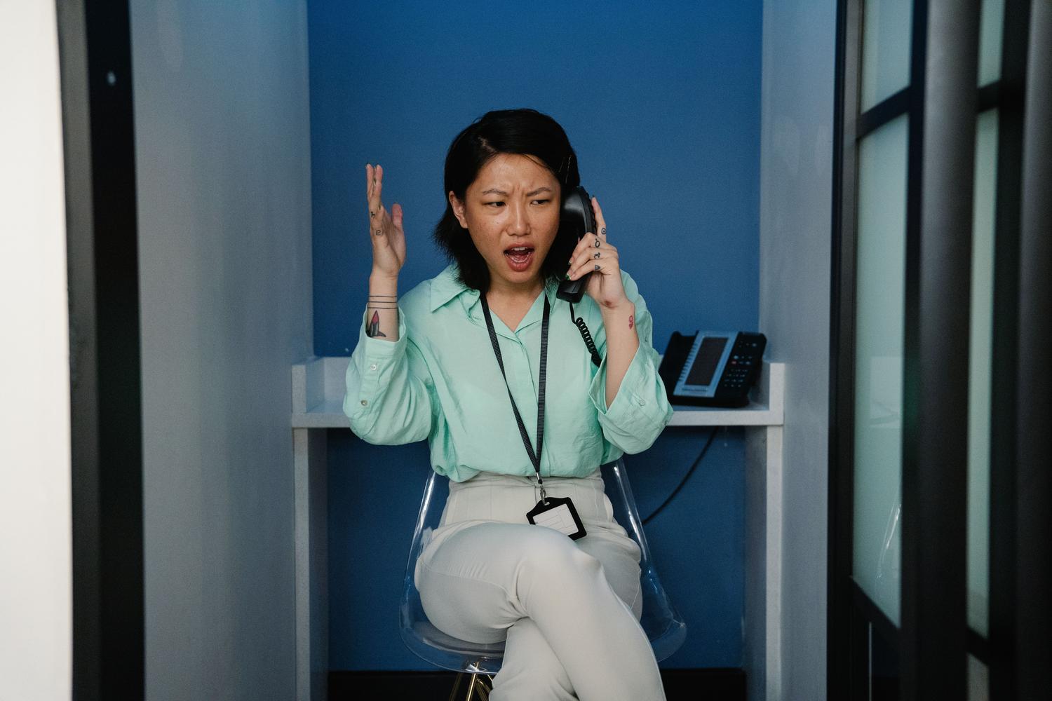 Mujer expresando frustración durante una llamada telefónica, representando la dificultad de no escuchar al interlocutor.