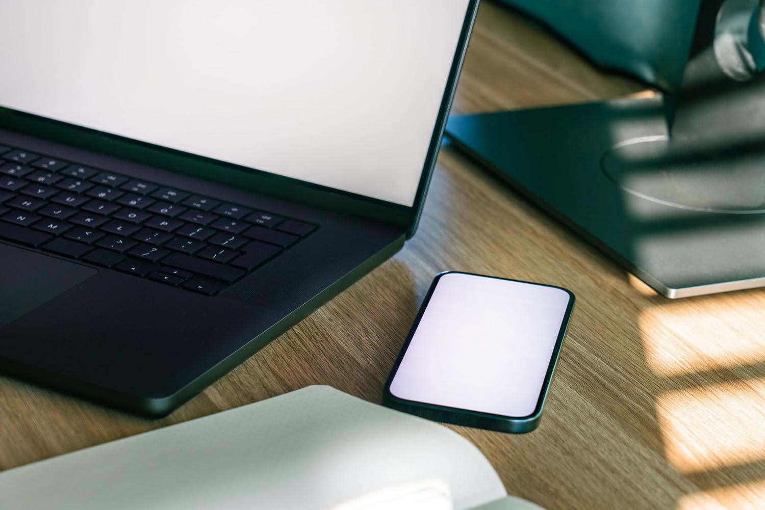 Escritorio de oficina moderno con un portátil y un smartphone, representando la interconectividad de los dispositivos