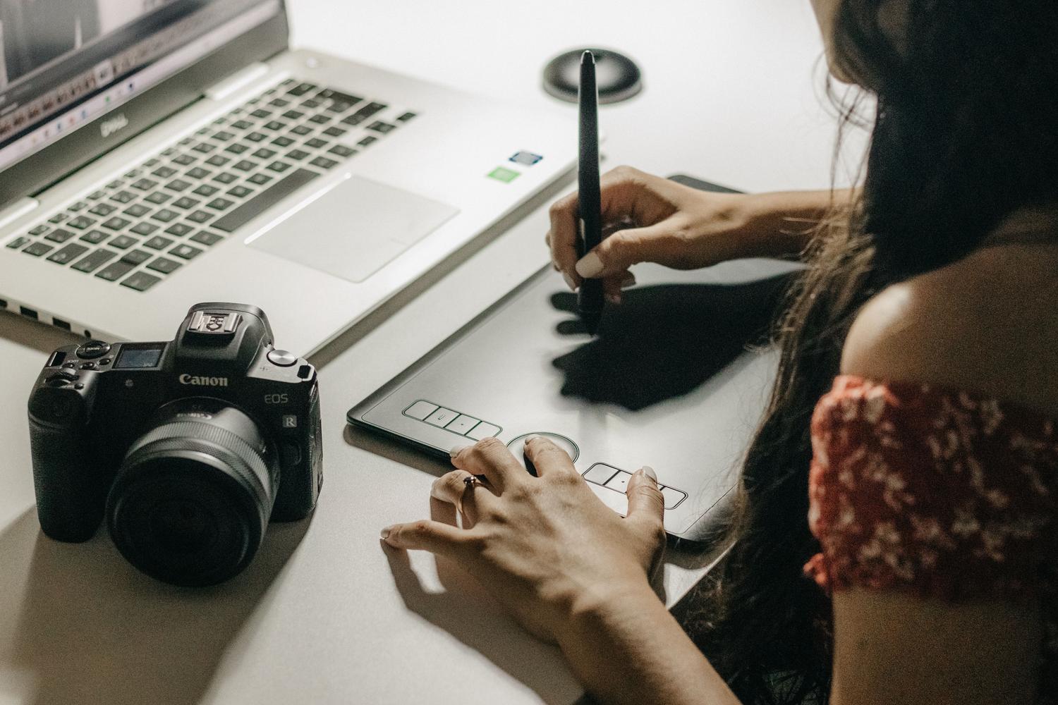 Mujer utilizando una tableta gráfica y un portátil en su espacio de trabajo creativo. Mujer utilizando una tableta gráfica y un portátil en su espacio de trabajo creativo.