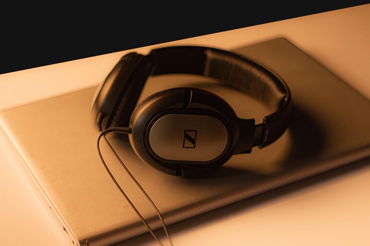 Auriculares de alta gama sobre un portátil con iluminación cálida, enfatizando la calidad del streaming y la fidelidad del sonido.