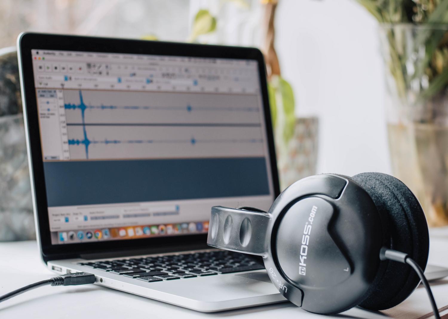 Primer plano de un ordenador portátil mostrando software de edición de audio y auriculares, ideal para ilustrar la sección de ecualización.