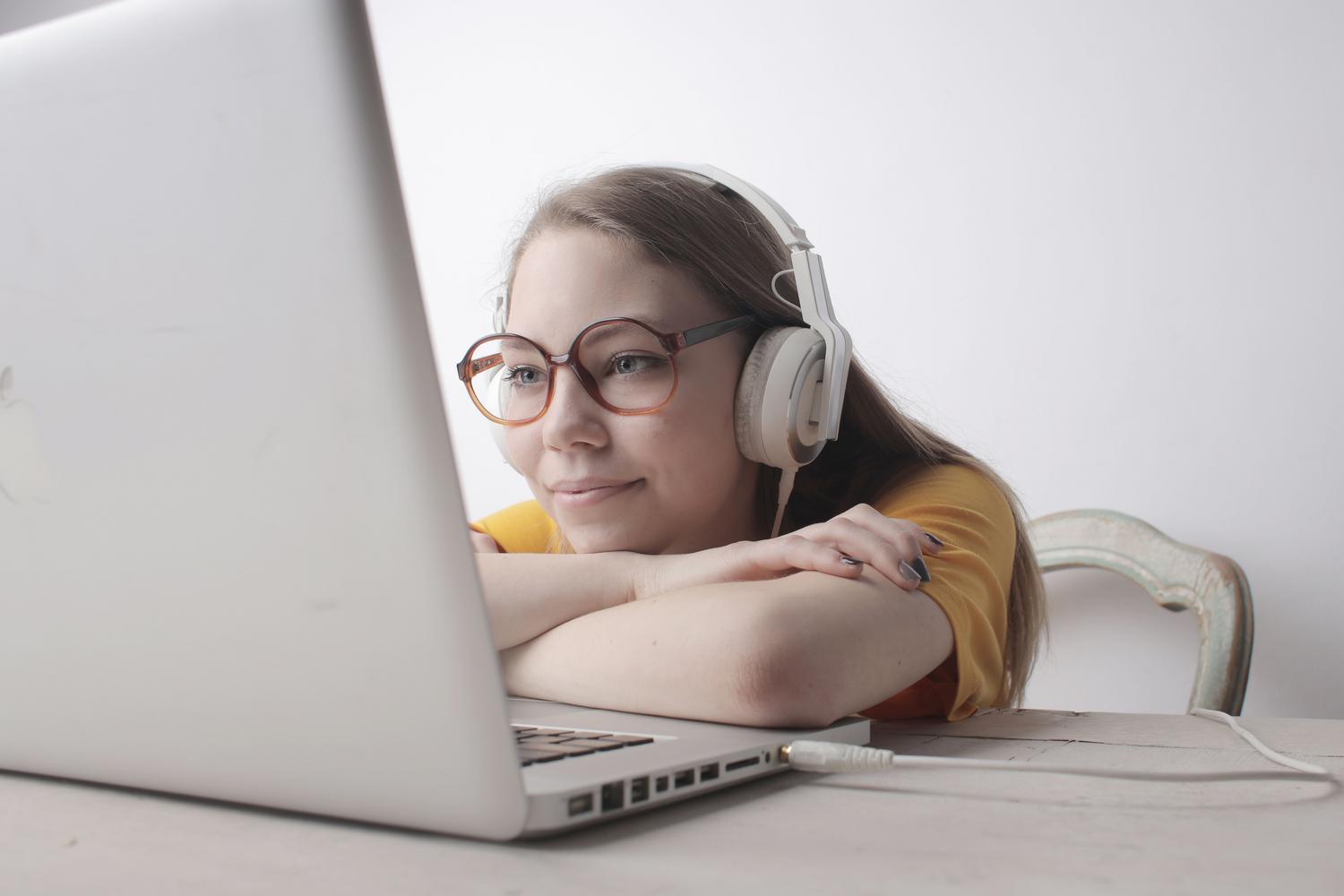 Mujer relajada utilizando auriculares y un ordenador portátil, ilustrando la experiencia de escucha optimizada.