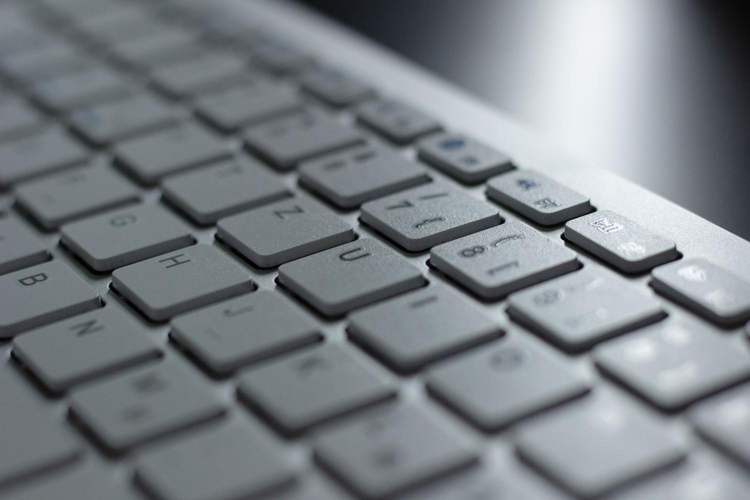 Detalle de un teclado moderno de aluminio con diseño minimalista y colores fríos.