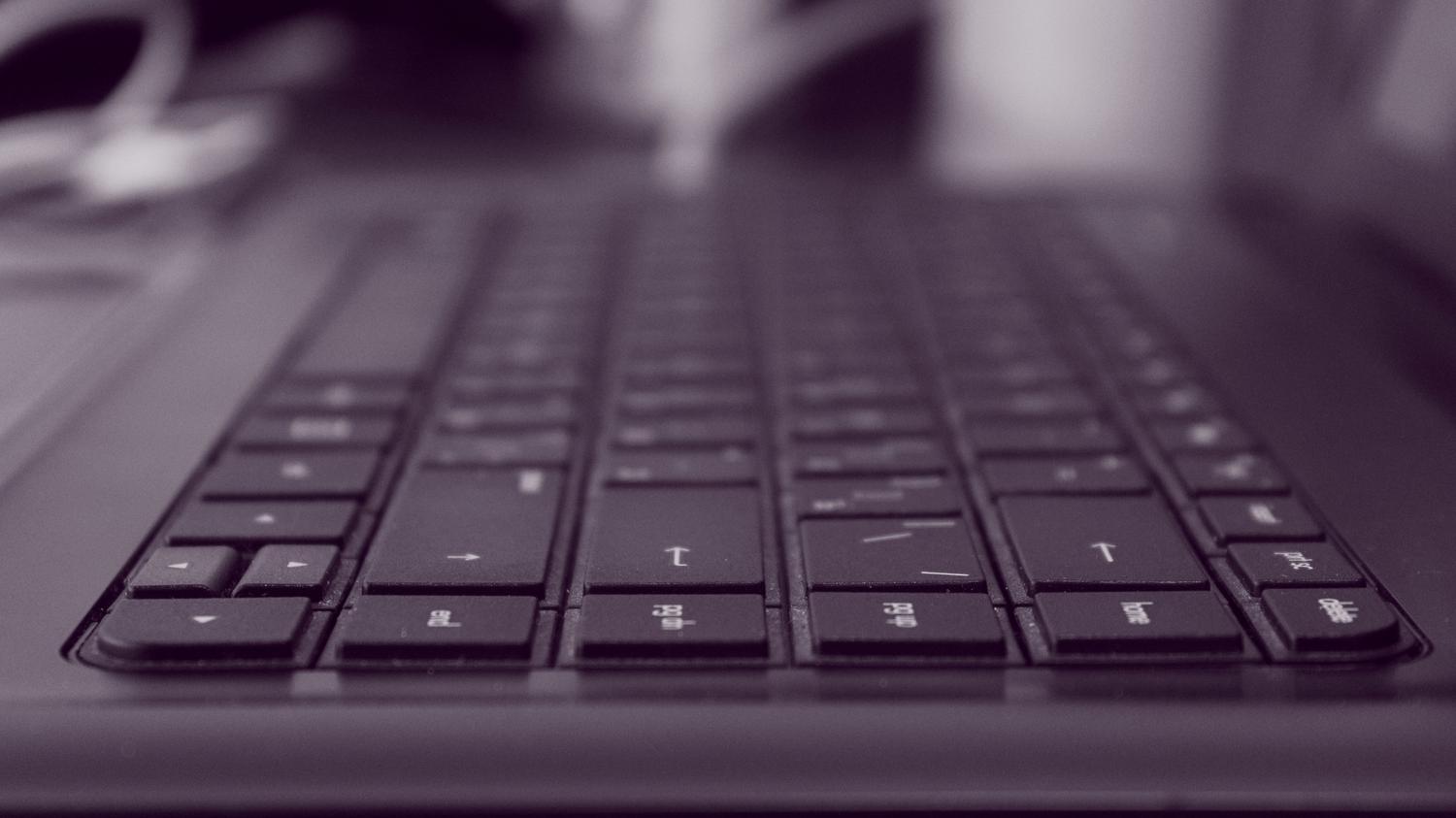 Primer plano artístico de un teclado de portátil tipo MacBook resaltando las teclas de comando y dirección.