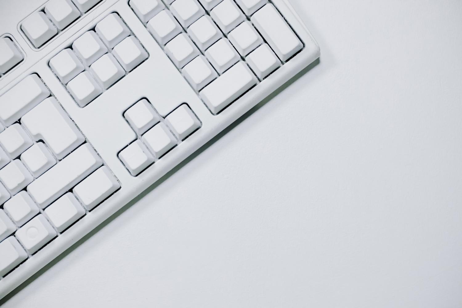 Teclado blanco sobre fondo blanco en una composición minimalista con amplio espacio negativo.
