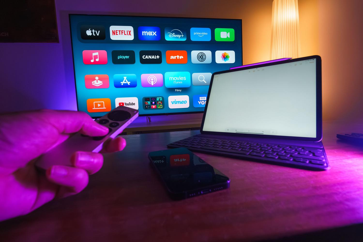Diversos dispositivos de streaming como Smart TV, tablet y móvil en un salón moderno, ilustrando la demanda de ancho de banda.