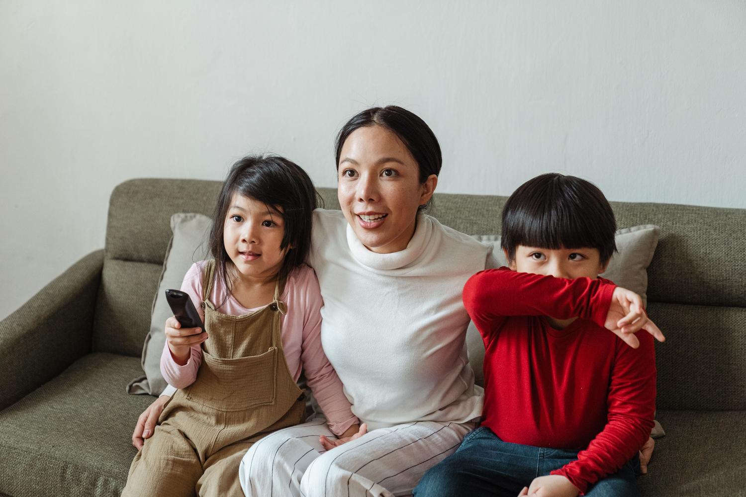 Madre y niños viendo la televisión juntos, representando la supervisión parental y un entorno digital seguro.