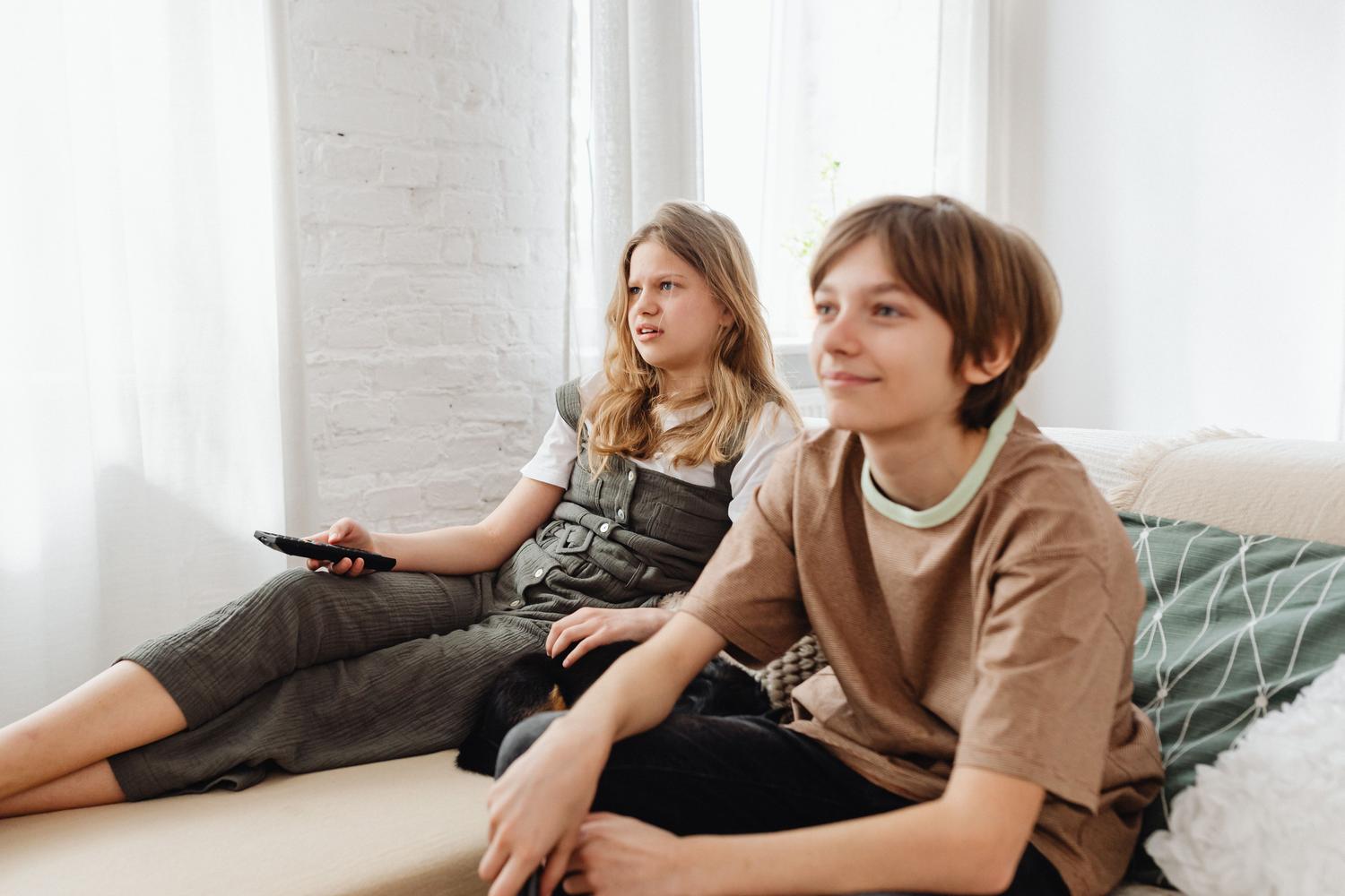 Dos niños viendo la televisión solos en el sofá, ilustrando la importancia de activar el control parental.
