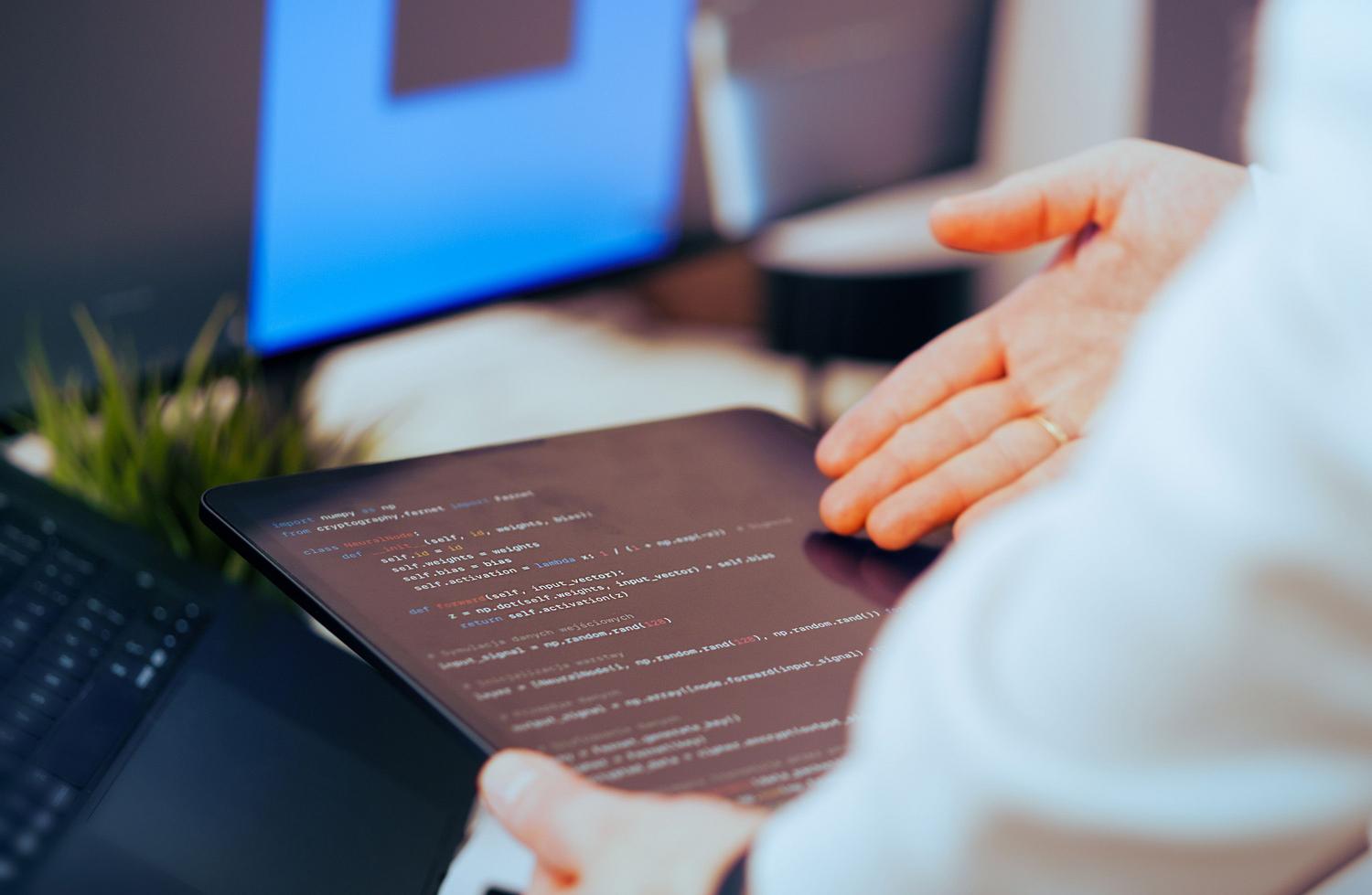 Desarrollador de software revisando código relacionado con IA en una tablet en una oficina moderna, simbolizando la capacidad técnica de Copilot.