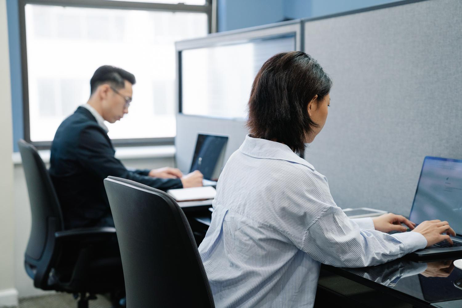 Profesionales enfocados trabajando con portátiles en un entorno corporativo contemporáneo y luminoso, reflejando la productividad digital moderna.