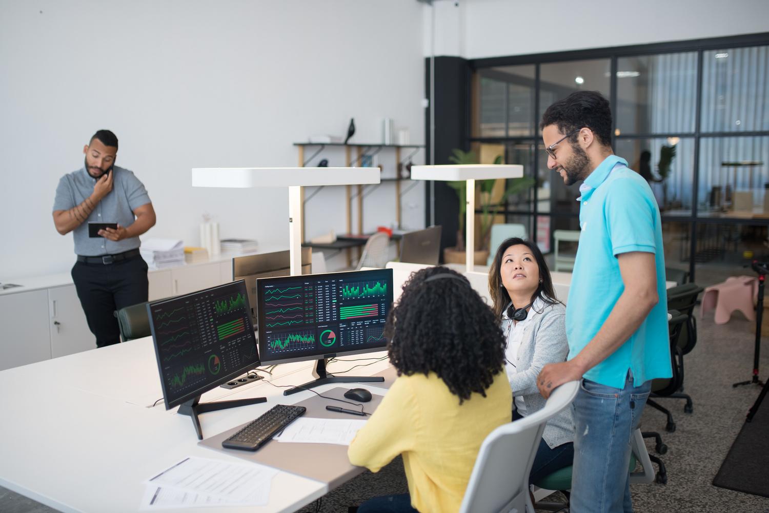 Profesionales analizando paneles de datos complejos en monitores múltiples en una oficina de alta tecnología, representando la inteligencia de negocio impulsada por IA.