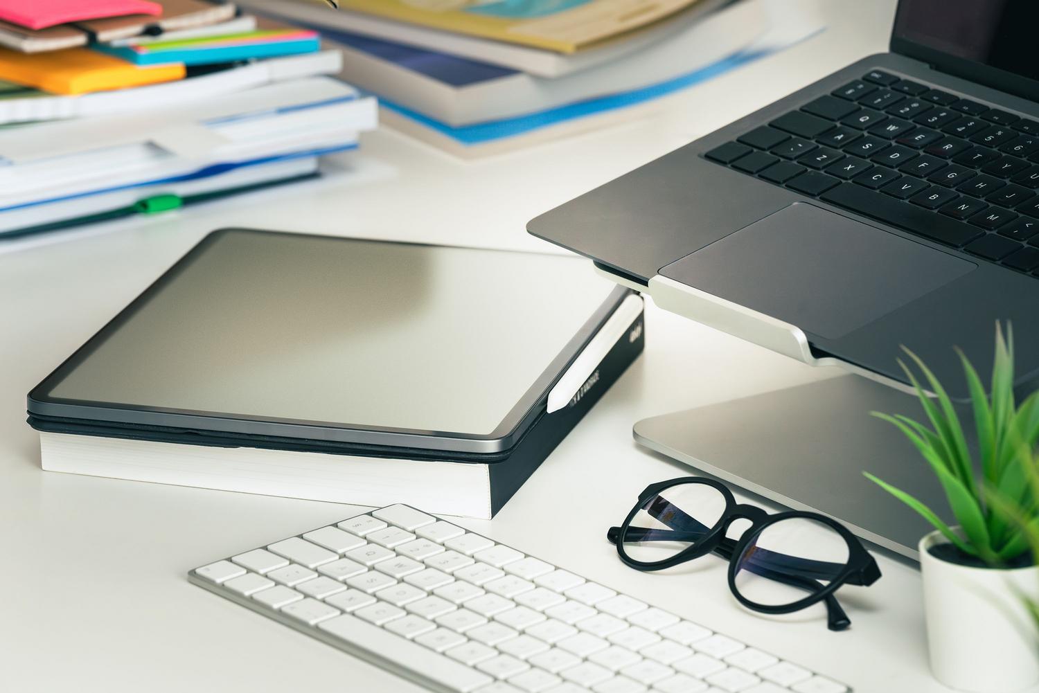 Espacio de trabajo moderno con un portátil y una tablet organizados sobre un escritorio blanco, ideal para representar la multitarea.