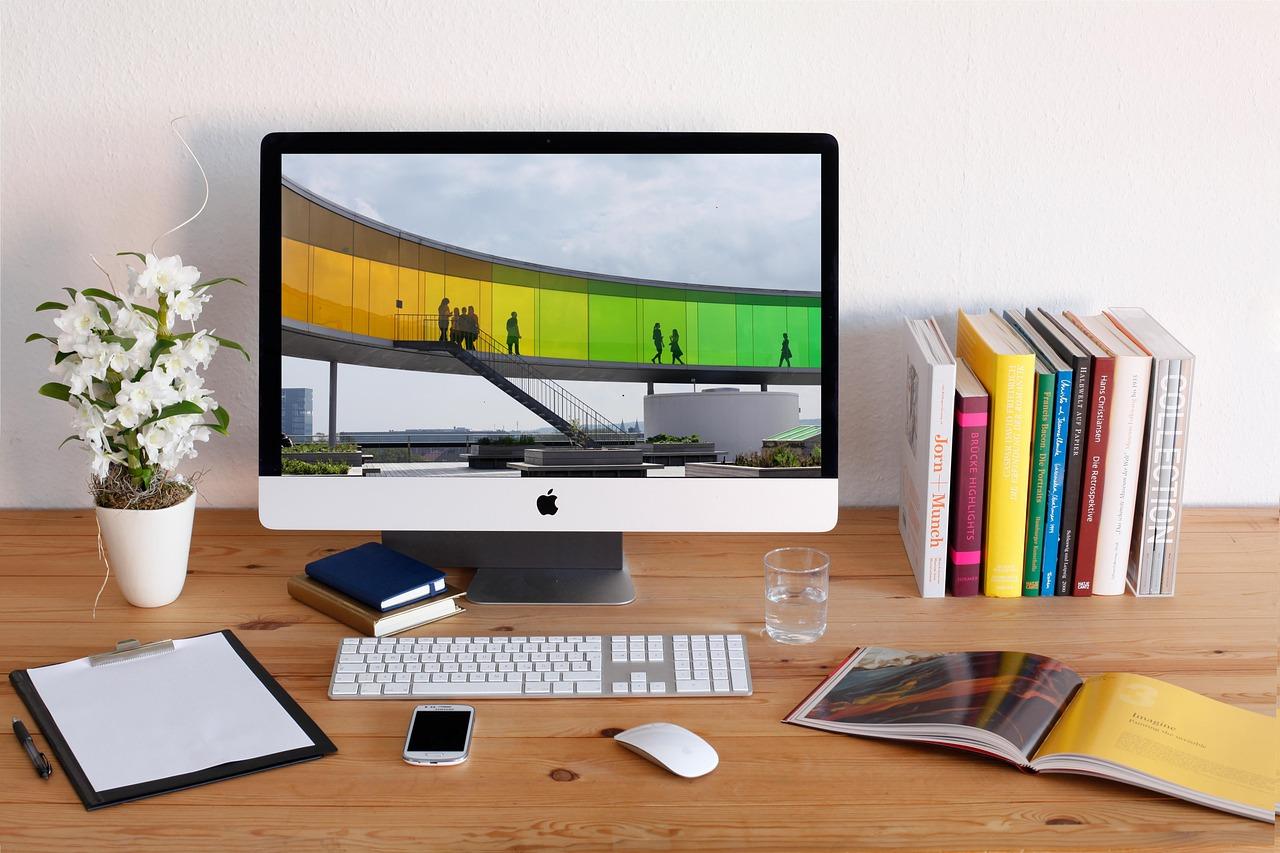 Configuración de oficina profesional en casa con un iMac y accesorios de escritorio organizados para un flujo de trabajo fluido.